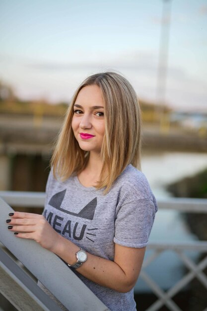 Vertical shot of a smiling caucasian female leaning on a fence