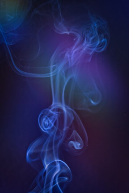 Photo a vertical shot of smoke in colorfull backlight with a blue note