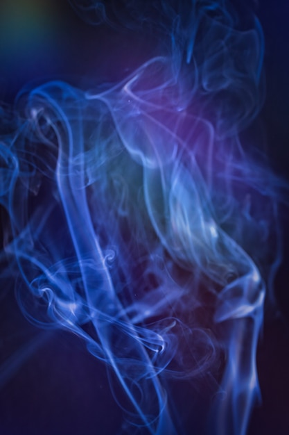 Photo a vertical shot of smoke in colorfull backlight with a blue note