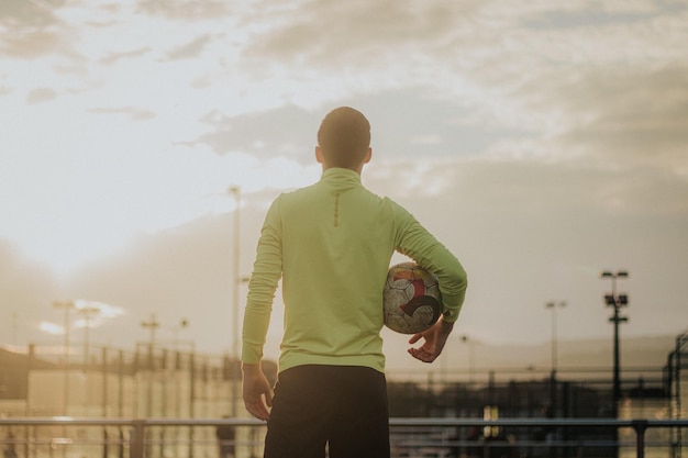 Vertical shot of soccer player with his back turned holding a\
soccer ball.