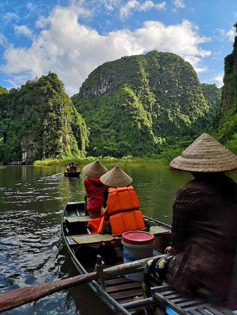 Foto fotografia verticale dei turisti che viaggiano in barca a ninh binh, in vietnam