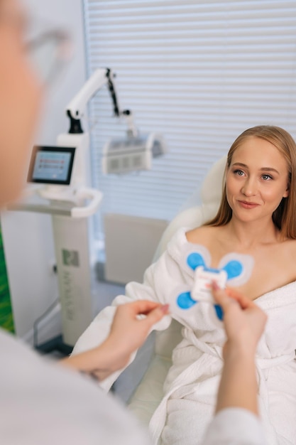 Vertical shot of unrecognizable female cardiologist attaching holter sensors on smiling woman