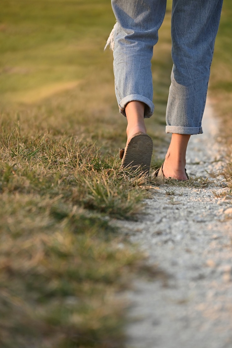 Vertical shot of an unrecognizable woman walking on a rural road, copy space, select focus