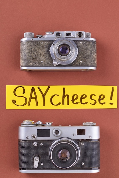 빨간색 배경에 있는 세로 샷 빈티지 사진 카메라는 치즈 필기 평면도를 말합니다.
