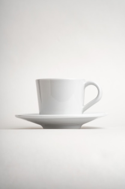 Vertical shot of a white little cup and saucer isolated on a white background