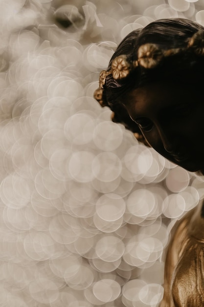 Vertical shot of woman statue on background of bokeh lights