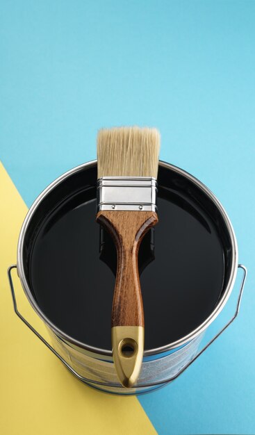 Vertical shot of Wooden paint brush on top of black color paint can with copy space