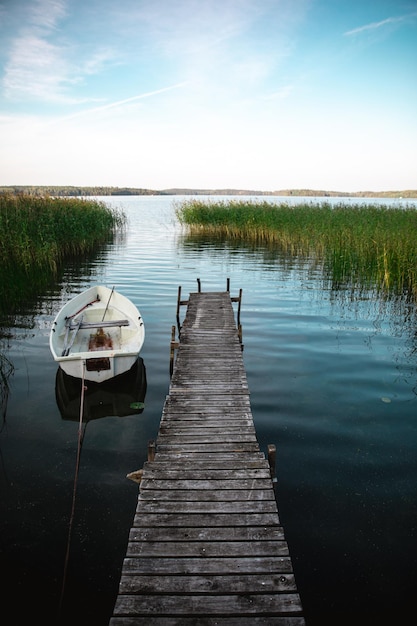 Vertical shot of a wooden pier and a boat on a calm lake during daylight