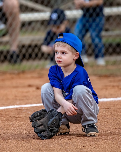 フィールド上でグローブでボールをキャッチする準備ができている若い愛らしい野球選手の垂直ショット