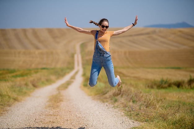 Vertical shot of a young female jumping on a path in the field