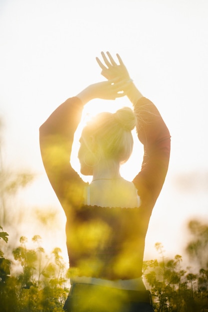 Vertical shot of a young female walking in a field of wildflowers and enjoying the beautiful sunset