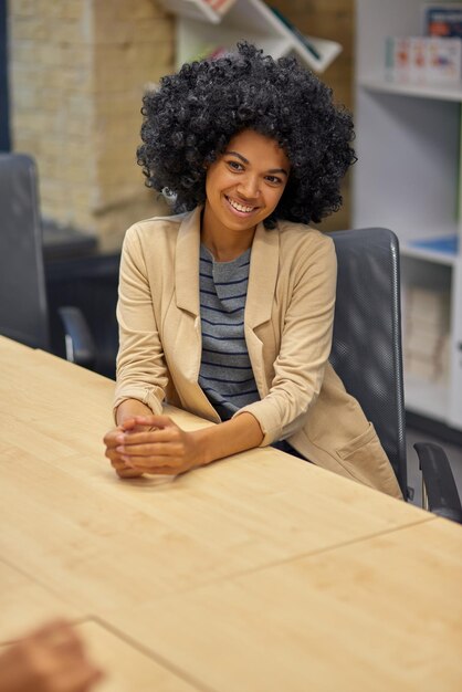 Vertical shot of a young happy mixed race woman female office worker sitting at desk
