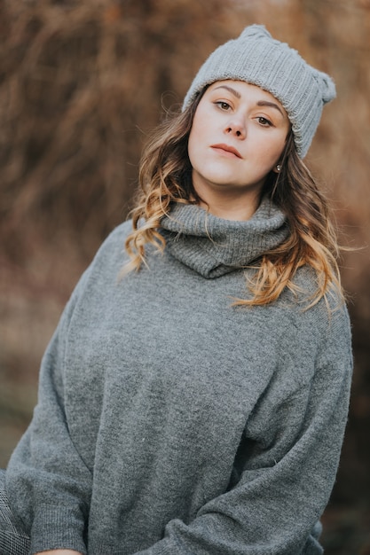 Vertical shot of a young lady wearing a gray turtleneck sweater and a hat