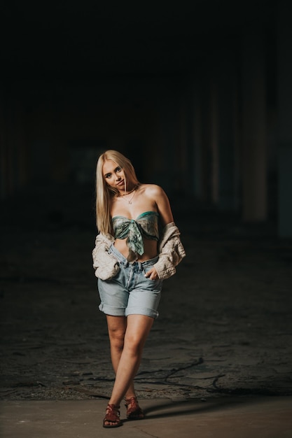 Vertical shot of a young sexy female posing in an abandoned building