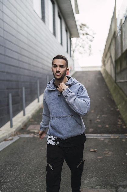 Vertical shot of a young trendy male in streetwear posing while walking