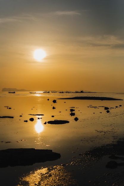 Vertical of silhouette fishing boats at sunset in the sea