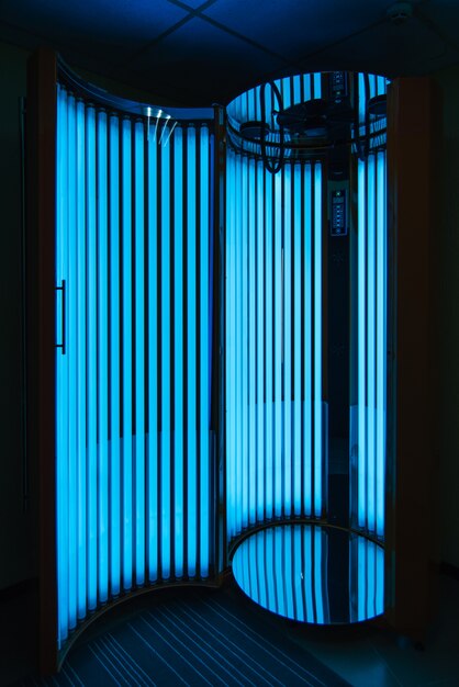 Vertical Solarium with glowing blue light ultraviolet lamps