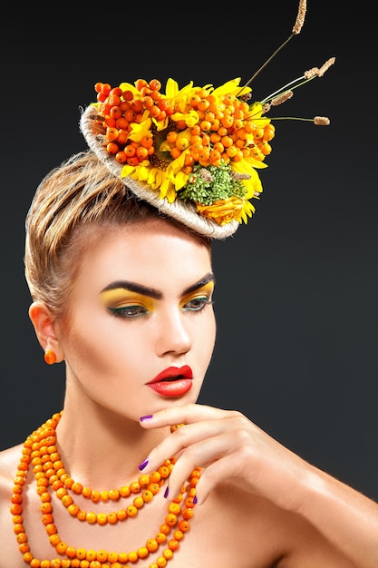 Ritratto verticale in studio di modella con bouquet di sorbo sulla testa e sorba sul collo