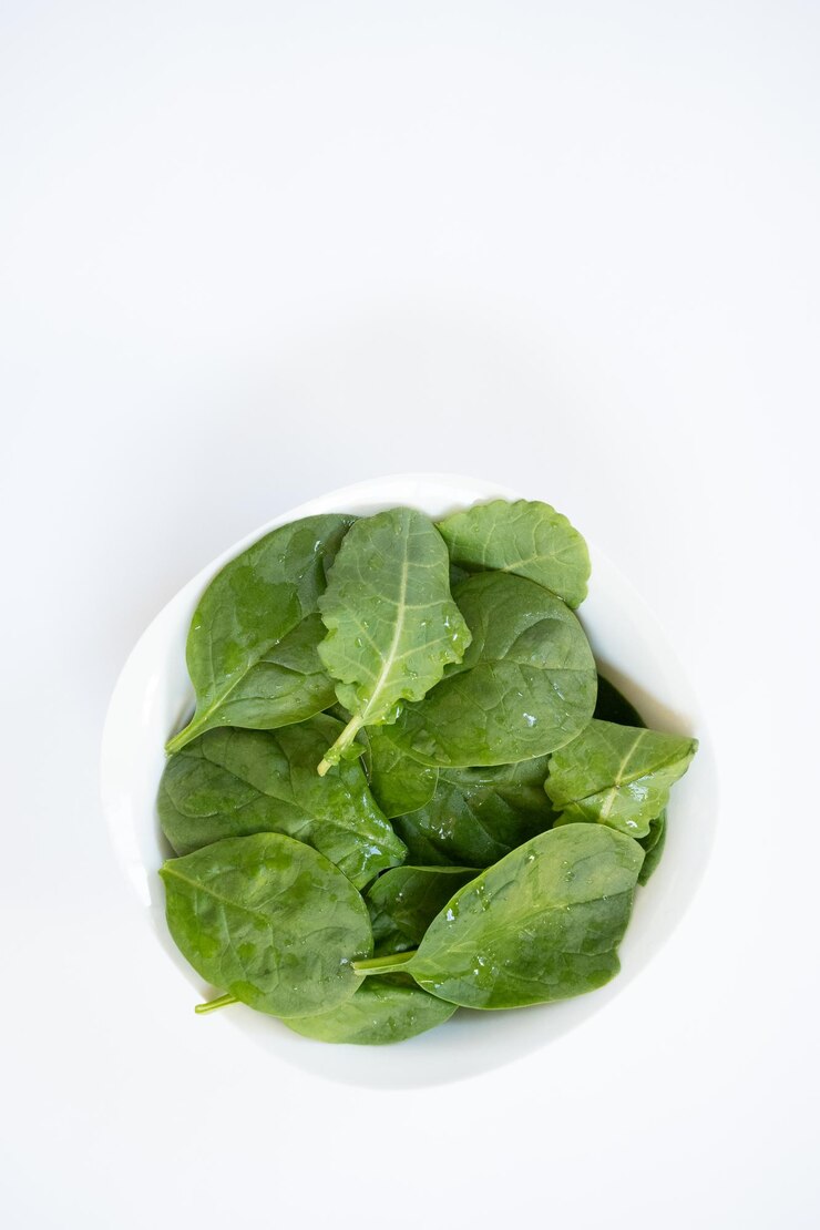 Vertical top view of leafy greens vegetables on white background with copy space