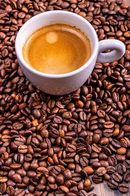 Vertical view of coffee cup on natural coffee beans International Coffee Day concept October 1st