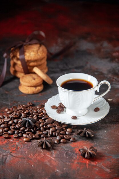 Foto vista verticale di delizioso caffè in una tazza bianca e fagioli arrostiti intorno biscotti impilati di lime alla cannella su sfondo di colore misto con spazio libero