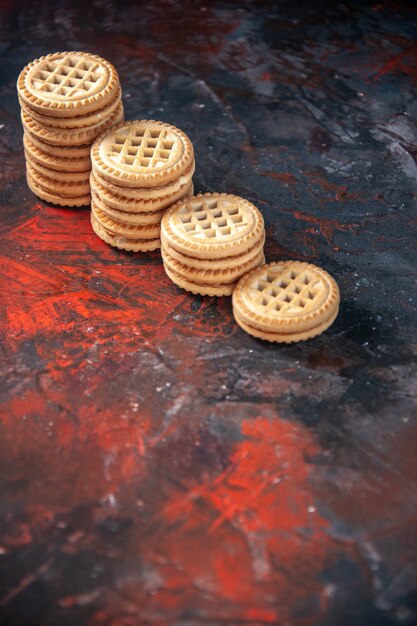 Vertical view of delicious cookies stacked in different numbers on mix colors background