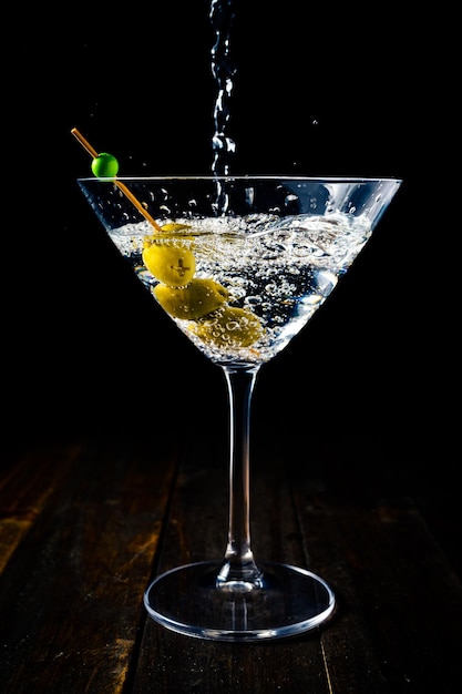 Vertical view of a dry martini glass with olives being served with the shot from above.