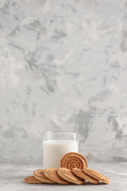 Vertical view of glass cup filled with milk and cookies on white surface