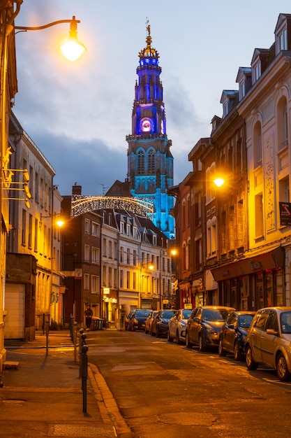 Вертикальный вид на освещенную колокольню с улицы в Аррасе, Франция