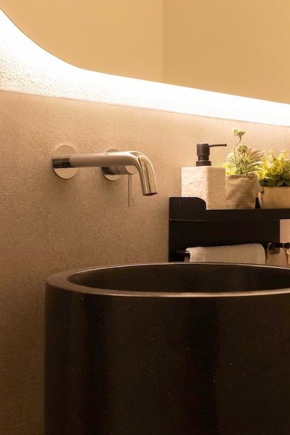 Фото Вертикальный вид современной ванной комнаты с черной раковиной из натурального камня и встроенным настенным краном