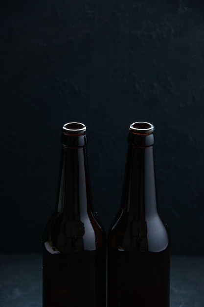 Photo vertical view of open glass bottles standing on table on dark wave background with free space