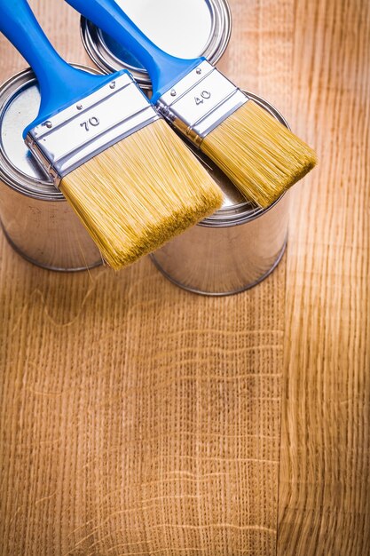 Photo vertical view organized copyspace two  paint brushes on  three cans and wooden board