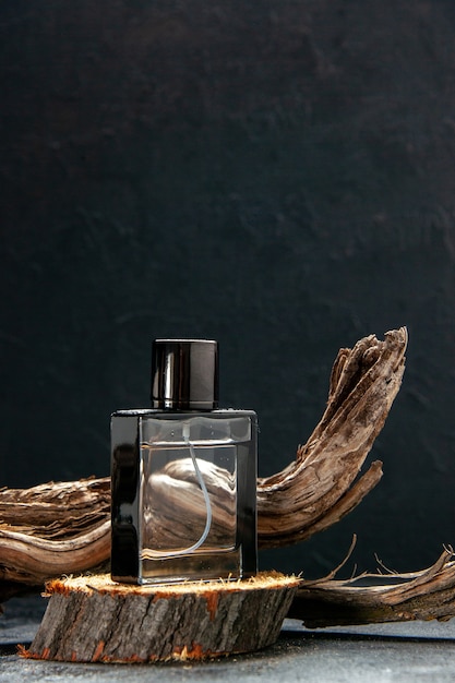 Photo vertical view of parfum on wooden cutting board and tree branch on light on dark background with free space