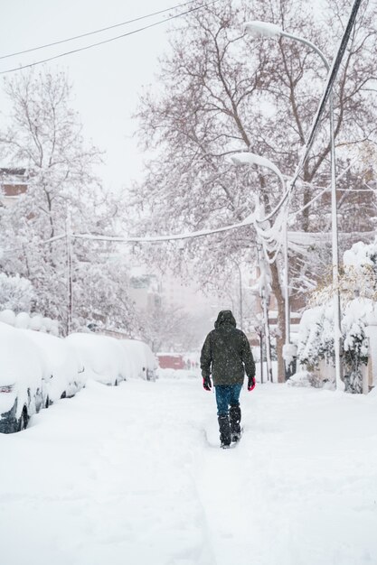 雪の真ん中で歩いている認識できない旅行者の垂直方向のビュー。