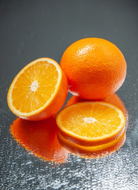 Vertical view of whole cut fresh oranges standing on dark color background with free space