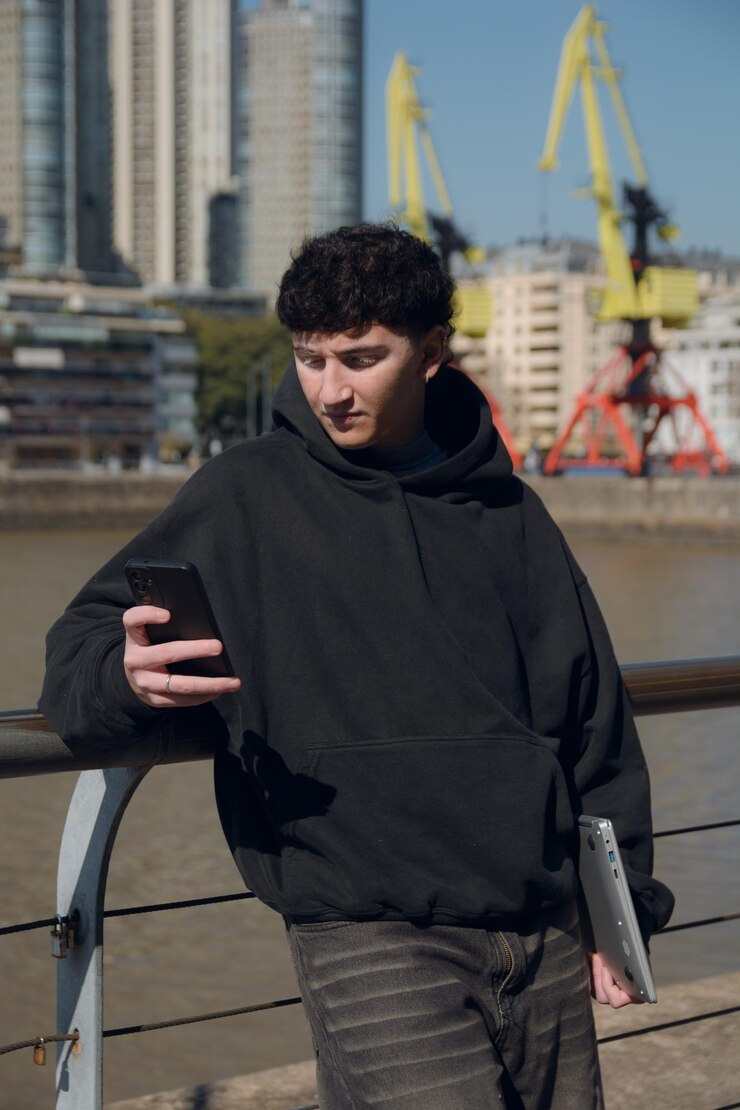 Verticale afbeelding van een jonge Argentijnse man die buiten sms'jes op zijn mobiele telefoon leest