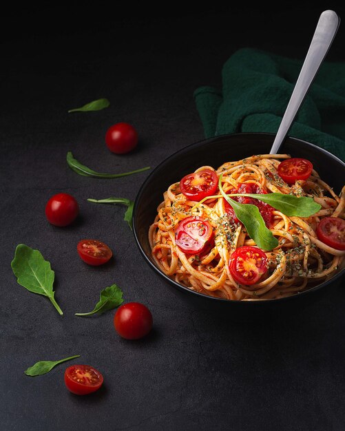 Foto verticale close-up shot van heerlijke pasta met cherrytomaatjes op een zwarte achtergrond