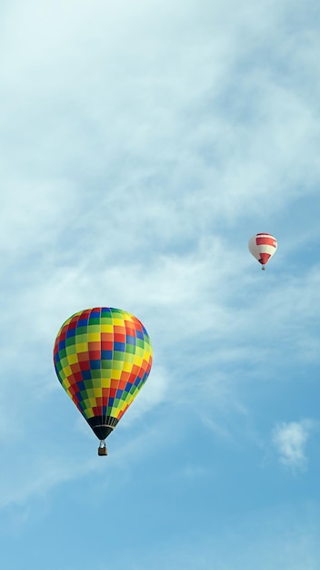 Verticale foto twee veelkleurige ballonnen vliegen hoog in de lucht