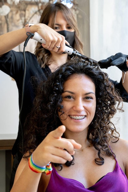 Verticale foto van een klant in een kapsalon die naar de camera wijst