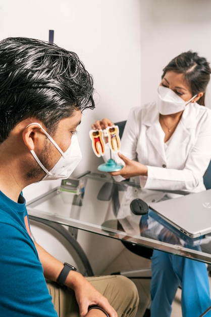 Foto verticale foto van een tandarts met een masker in gesprek met een klant in een tandheelkundige kliniek