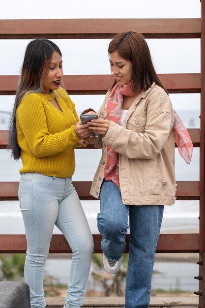 Verticale foto van twee vrouwen die een mobiel gebruiken op straat