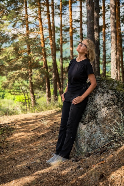 Verticale frames volwassen vrouw rustend leunend tegen rotsbos baden achtergrond vakantie idee