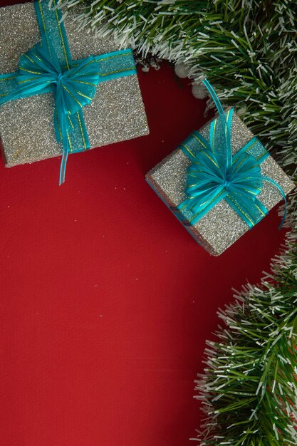 Verticale kerstachtergrond met geschenkdozen met blauwe strik groene takken en rode achtergrond