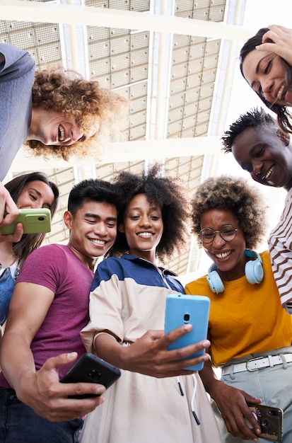 Foto verticale lage hoekfoto van een groep jonge tieners met mobiele telefoons