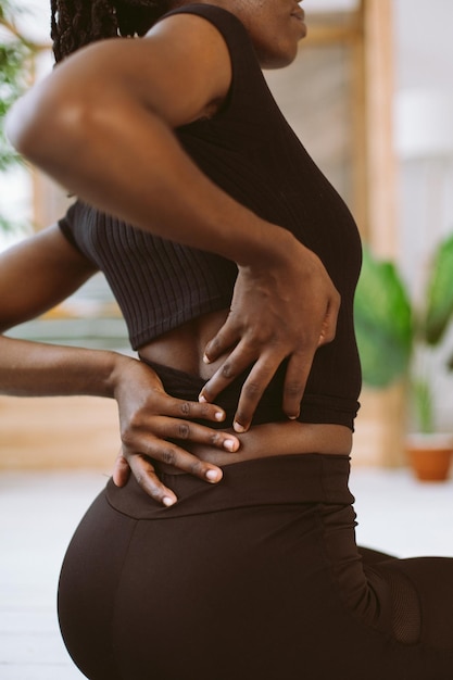 Verticale multiraciale vrouw met dreadlocks die zich uitstrekken, doen yoga-oefeningen op buigende benen Rugpijn na training