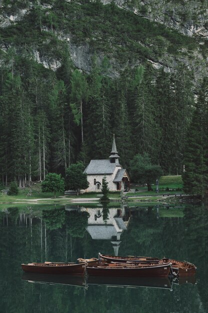 Verticale opname van de prachtige bergen en het meer met een kerk en boten in Zuid-Tirol, Italië