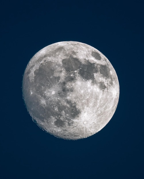 Foto verticale opname van een glanzende volle maan in de blauwe hemel's nachts