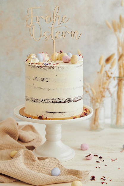 Verticale opname van een heerlijke Happy Easter (Frohe Ostern) naakte cake op een witte tafel