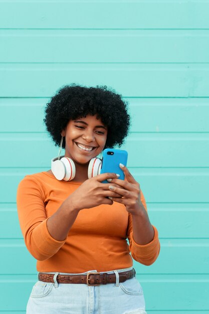 Verticale opname van een jonge aantrekkelijke dame die een koptelefoon draagt met haar telefoon