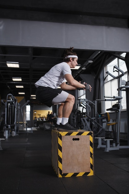 Verticale profielfoto van een sportman die op een doos springt bij een functionele trainingshal